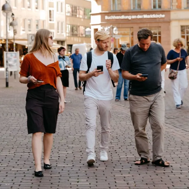 Drei Personen gehen mit Smartphones durch die Hannoveraner Altstadt